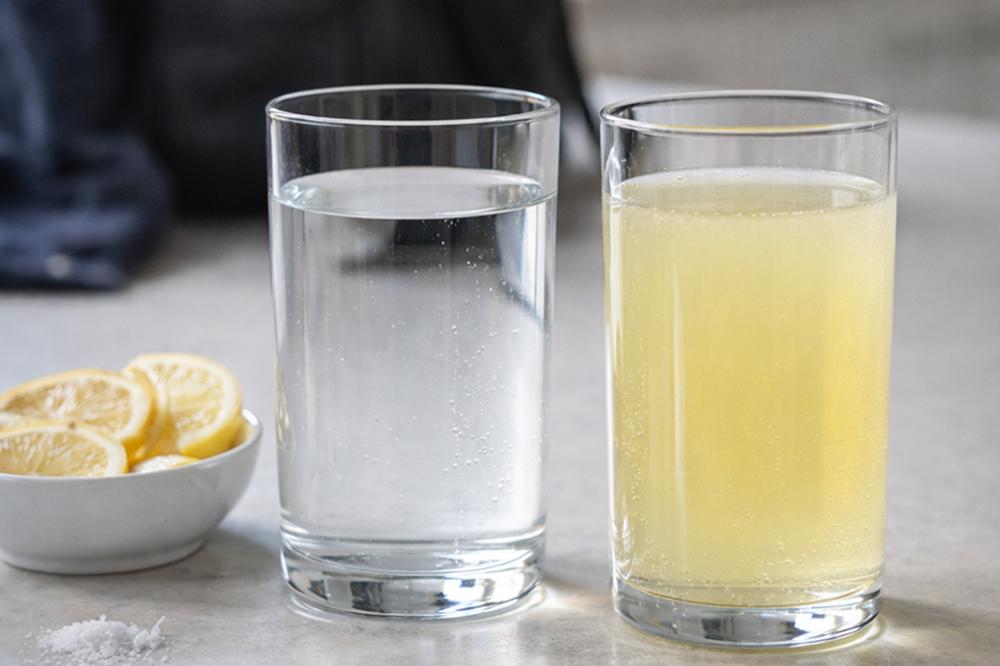 На кухонной столешнице стоят два стакана — вода и изотоник — рядом спортивная сумка и полотенце